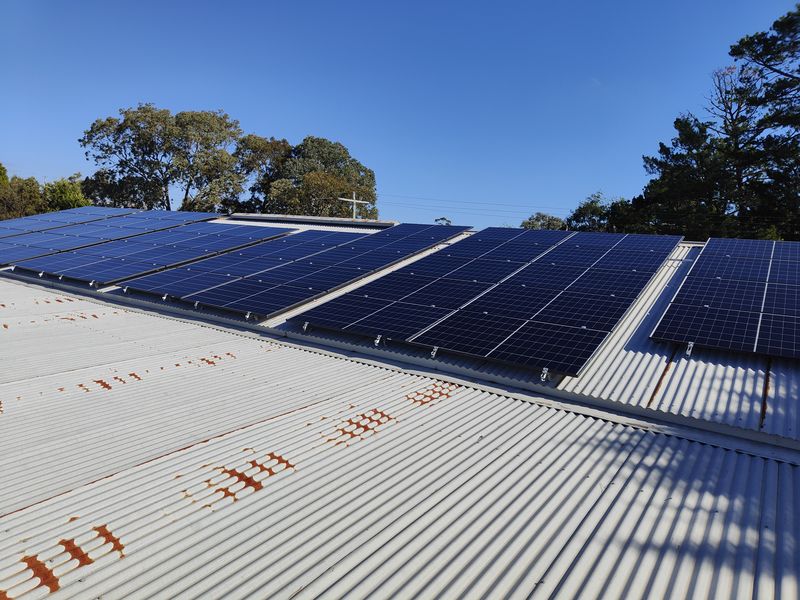 Happy Australian family standing in front of their home with solar panels on the roof